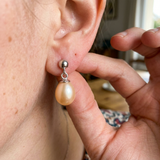Boucles d'oreilles en or blanc 9 carats avec perle de culture rose portées à l'oreille.