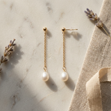 Boucles d'oreilles pendantes or jaune 9 carats avec chaîne fine et perle blanche ovale.