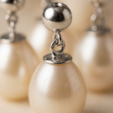 Gros plan sur la perle de culture et le fermoir boule en or blanc d'une boucle d'oreille.