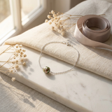 Bracelet argent 925 chaîne fine avec perle noire de Tahiti, posé sur marbre.