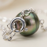 Gros plan sur le fermoir anneau d'un bracelet en argent 925 avec perle noire de Tahiti.
