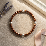 Bracelet en argent 925 avec perles d'eau douce chocolat et blanches, posé à plat.