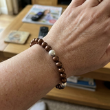 Bracelet en argent 925 avec perles d'eau douce chocolat et blanche porté au poignet.