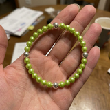Bracelet en argent 925 avec perles d'eau douce vertes, tenu dans une main.