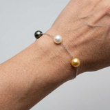 Bracelet argent 925 porté au poignet avec trois perles : Tahiti noire, eau douce blanche et dorée.