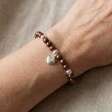 Bracelet perle d'eau douce chocolat et argent 925 avec charm cœur porté au poignet.