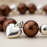 Bracelet perle d'eau douce chocolat argent 925 avec charm cœur en gros plan.
