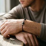 Bracelet homme en coton ciré noir avec perle de Tahiti et nœuds argent, porté au poignet.