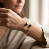 Bracelet jonc en argent 925 porté au poignet, avec deux perles de Tahiti noires aux extrémités.
