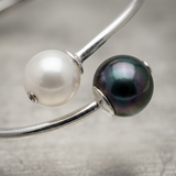 Bracelet jonc argent 925 avec perle blanche et perle noire côte à côte, gros plan.