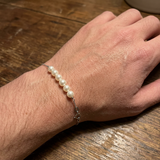 Bracelet or blanc 9 carats et perles blanches porté au poignet.