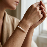 Bracelet or blanc 9 carats et perles blanches porté au poignet sur fond clair.