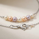 Bracelet or blanc 9 carats avec perles multicolores roses, mauves et blanches sur chaîne, fermoir homard visible.