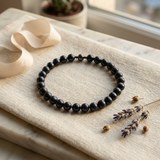 Bracelet perle d'eau douce noire argent 925 posé à plat sur lin beige.