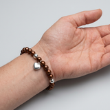 Bracelet perles d'eau douce chocolat et argent 925 avec charm cœur, porté au poignet.