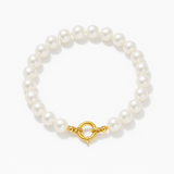 Bracelet de perles blanches rondes avec fermoir anneau en or jaune 9 carats sur fond neutre.