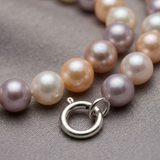 Gros plan sur le fermoir anneau en argent 925 d'un bracelet de perles multicolores.