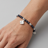 Bracelet perles d'eau douce noires et argent 925 avec charm trèfle, porté au poignet.