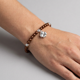 Bracelet perles d'eau douce chocolat et argent 925 avec charm trèfle porté au poignet.