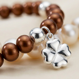 Gros plan sur bracelet perles d'eau douce chocolat et argent 925 avec pendentif trèfle.