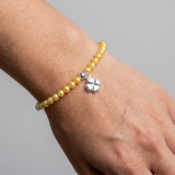 Bracelet perles d'eau douce dorées avec charm trèfle en argent 925 porté au poignet.