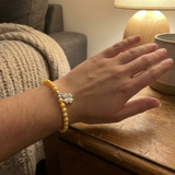 Bracelet perles d'eau douce dorées avec charm trèfle en argent 925 porté au poignet.