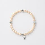 Bracelet perles d'eau douce roses et argent 925 avec charm cœur sur fond blanc.