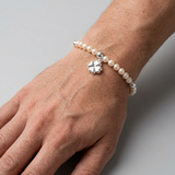 Bracelet perles d'eau douce roses et argent 925 avec charm trèfle porté au poignet.
