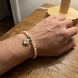 Bracelet perles d'eau douce roses et argent 925 avec charm trèfle porté au poignet.