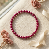 Bracelet perles d'eau douce rouge cerise sur argent 925, posé à plat sur tissu beige.