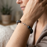 Bracelet perles noires 8/9 mm en argent 925 avec fermoir mousqueton porté au poignet.