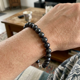Bracelet en perles noires 8/9 mm avec fermoir mousqueton en argent 925, porté au poignet.
