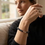 Bracelet perles noires et argent 925 au poignet d'une femme, fermoir mousqueton visible.
