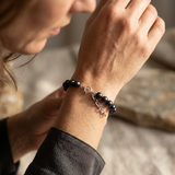 Bracelet perles noires argent 925 porté au poignet, fermoir anneau réglable visible.