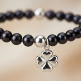 Bracelet perles noires avec charm trèfle quatre feuilles en argent 925, gros plan sur le pendentif.