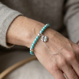 Bracelet perles d'eau douce turquoise et argent 925 avec charm trèfle porté au poignet.