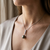 Collier en argent 925 avec pendentif perle noire et barre pavée de zircons, porté au cou.