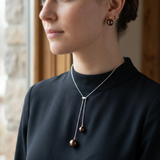 Collier et boucles d'oreilles à perles chocolat portés sur col montant noir.