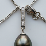 Gros plan sur pendentif argent 925 à barre de diamants et perle noire de Tahiti baroque.