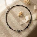 Collier ras le cou en coton ciré noir avec une perle de Tahiti, présenté à plat.
