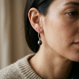 Boucles d'oreilles créoles argent 925 avec perle de culture noire de Tahiti portées à l'oreille.
