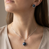 Collier et boucles d'oreilles à perle noire sertie en fleur, portés au cou et à l'oreille.