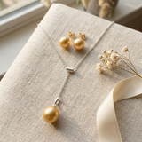 Collier pendentif et boucles d'oreilles puces ornés d'une perle dorée sur chaîne argentée.