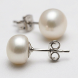 Puces d'oreilles en or blanc 9 carats serties de perles blanches, fermoir papillon visible.